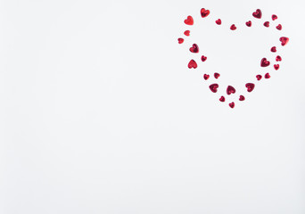 Valentines decoration of red confetti in shape of  hearts on white background. Top view. Copy space. Flat lay