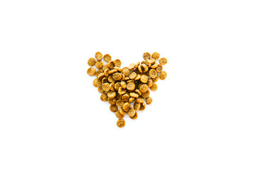 Dry pet food is laid out in the shape of a heart. Isolated pellets feed for cats or dogs. Food for sterilized cats or dogs. Hypoallergenic food. Selective focus.