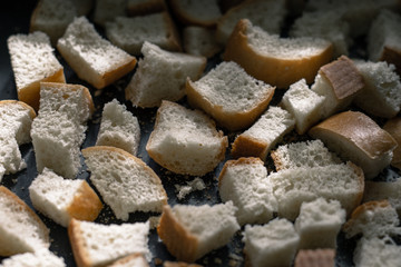 Finely diced dried bread. Finely chopped bread. Small pieces of bread. Square slices of bread. Rusks on a tray