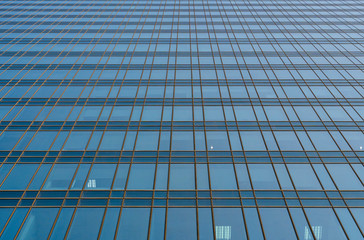 Fototapeta na wymiar Reflection of the sky in the windows of a building. Perspective and underdite angle view to modern glass building skyscrapers over blue sky. Windows of Bussiness office or corporate building.