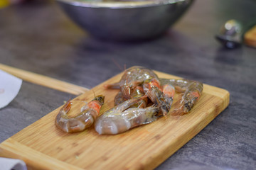 Raw Prawns laying on the wooden board kitchen preparations