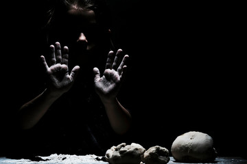 Little cute girl chef cooking with white flour on black background