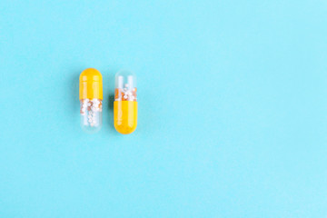 two medicine capsules on blue background with copy space flat lay