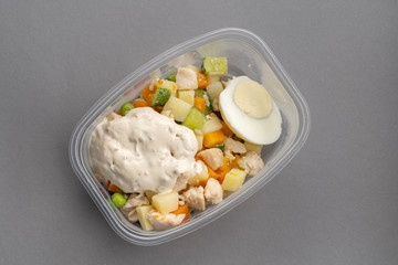 Olivier salad in plastic plate on gray background. Top view.