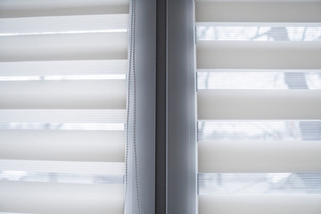 Details of white fabric roller blinds on the white plastic window in the living room. Close up on...