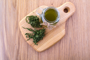 Obraz na płótnie Canvas Hemp oil in a glass jar, cannabis leaves on the background of the wooden boards. Top view.