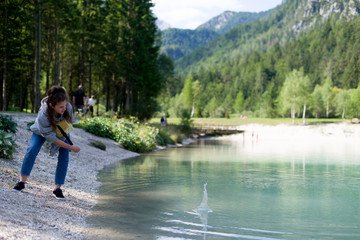 Fototapeta premium Girl throws stones in water in national park