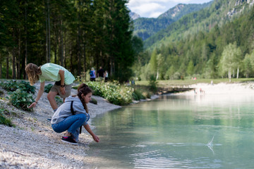 Girl and boy  throws stones in water in national park