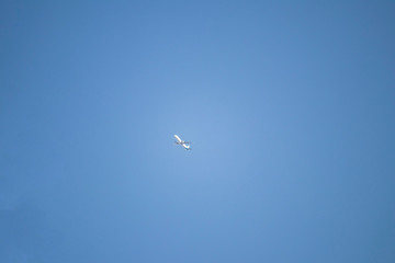 AN airplane is flying from east to west. The sky is perfectly blue.