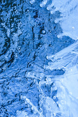 Blue ice and blue bubbling water. A variety of ice patterns and shades of blue in glacial ice and water.Background image for spa salon. Flat lay .Copy-Space