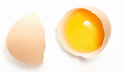 broken chicken egg with yolk in one half of the shell