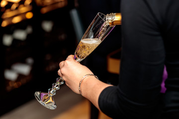 Female pouring champagne in a champagne glass with a blurred background