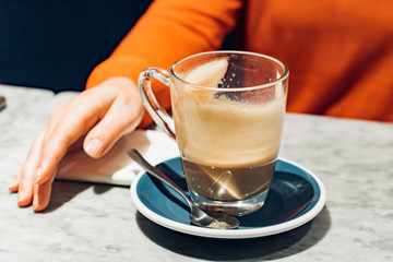 Young woman in orange jumper drinking latte