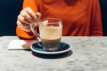 Young woman in orange jumper drinking latte