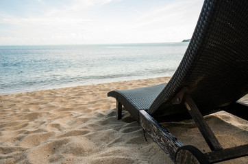 Brown beach chairs on perfect tropical sand beach near blue water of sea in a sunny day.
