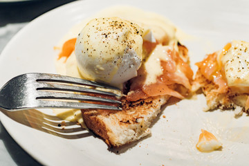 Nibbling on poached eggs with smoked salmon on toast
