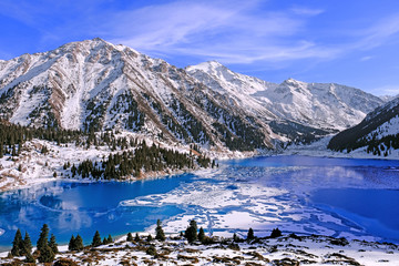 Autumn gives way to winter, air temperature drops and the water in the lake begins to freeze. Texture and patterns of ice on the serene water surface of a mountain lake; Big Almaty lake in Kazakhstan