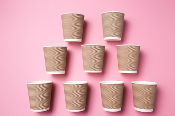 Paper cup for hot coffee or tea on a pink isolated background.