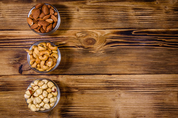 Various nuts (almond, cashew, hazelnut) in glass bowls on a wooden table. Vegetarian meal. Healthy eating concept. Top view