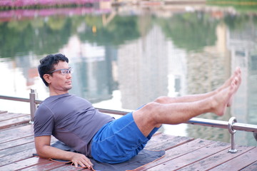 young man sitting on a bench in the park​ yoga​​ Exercise