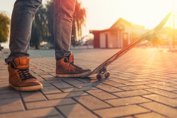 Skateboarding. The man put his foot on the skateboard. Close up. Sunset light