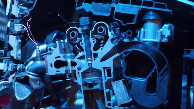 A closeup of a cut section of an internal combustion engine in blue light.