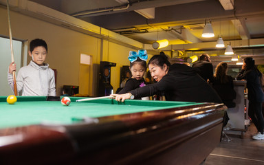 Group of happiness asian family mother, son and daughter playing billiard