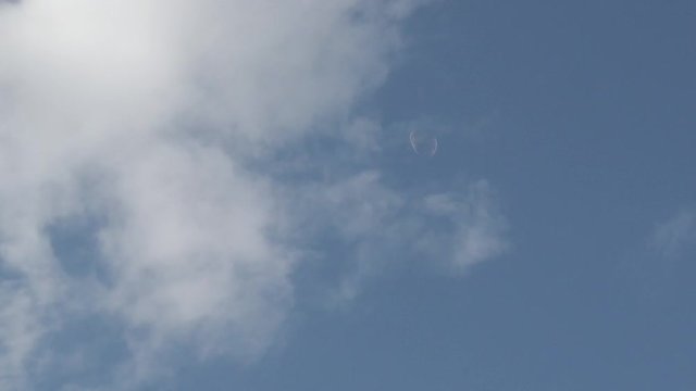 Slow motion view of soap balloons floating in a light blue sky guided by wind