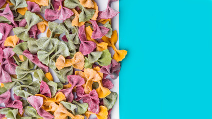 Pile of Italian dried Tri Color Farfalle pasta. Various colors of bow tie on blue color background