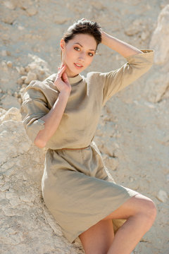 Slim oriental girl in khaki dress on sand