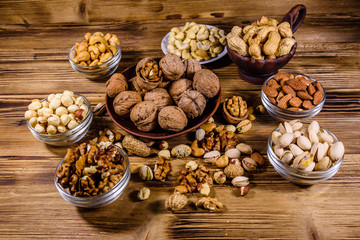 Various nuts (almond, cashew, hazelnut, pistachio, walnut) in bowls on a wooden table. Vegetarian meal. Healthy eating concept