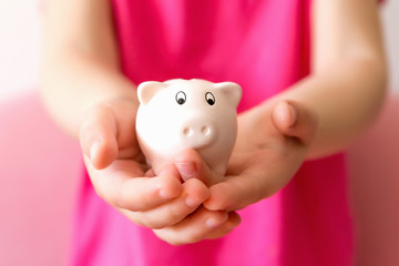 Fototapeta na wymiar Pink piggy bank on children hands. Close up, selective focus.