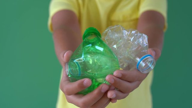 Closeup view of young kid hands holding several empty plastic crumpled bottles in hands. Real time 4k video footage.