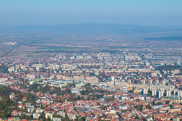 Fototapeta na wymiar Brasov city seen from the Tampa mountain on a fall day. landscape shoot with mountain blurred on the background and the city buildings in front of the screen