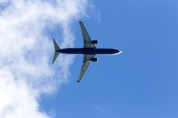 Low angle view of plane against sky, close up fling. Blue plane, low cost flights company, passenger airplane flight against blue background below view
