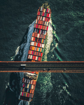 Cargo ship under bridge during day