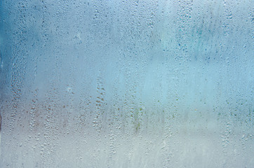 Indoor wet window on which droplets of water slide.