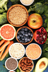 Healthy food clean eating selection: fruit, vegetable, seeds, superfood, cereals, leaf vegetable on rustic background