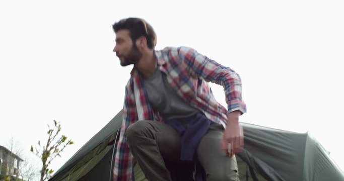 adventure hipster man cooking breakfast or lunch near hi camping tent. backpacker man camping in rural area. Close shot. Man camping trip.Man preparing campfire.