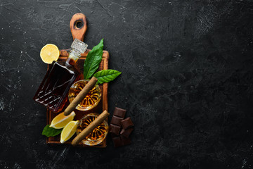 Whiskey in glasses and Cuban cigars on a black stone table. Top view. Free space for your text.