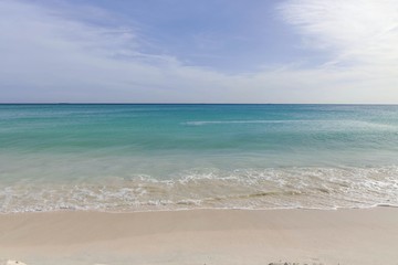 Fototapeta na wymiar White sand beach and turquoise waves. Turquoise sea water and blue sky. Eagle Beach of Aruba Island. Beautiful backgrounds.