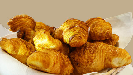Several fresh croiisants lie in a basket. Bakery concept.