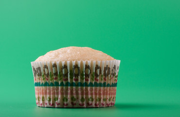 Delicious sweet cupcake without icing sugar, green background
