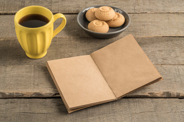 blank notebook, coffee and cookies on a wooden table