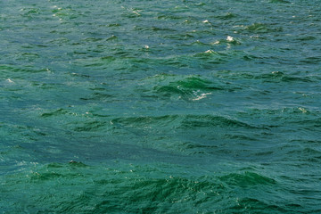 Day view of rough sea with waves due to strong surface winds. An open empty green blue sea with low waves rising in various formations.