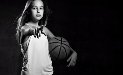 Beautiful caucasian teen woman in sportswear playing basketball . Sport concept isolated on black background.