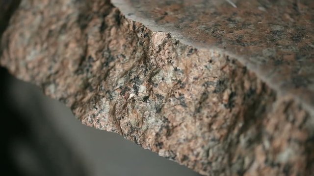 Uneven section of granite raw stone slab, closeup view.