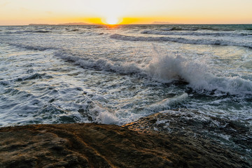 Bright sea sunset. The waves crash into the rock. The sea wave breaks into splashes and white foam. Never-ending beauty of nature. Logas Beach, Sidari, Corfu, Greece, Europa.