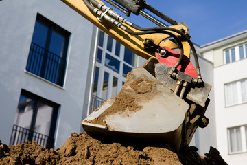 Excavator bucket digs sand on block background © Andrei