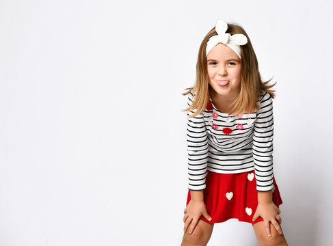 Happy child little girl in a red skirt and a striped T-shirt, with a perky hairband - has fun on a light background